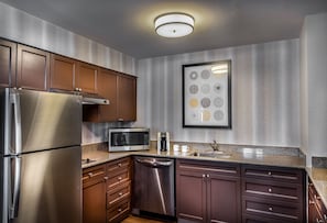 A modern kitchen with stainless steel appliances, wooden cabinets, and a granite countertop. - Residence Inn by Marriott Washington, DC National Mall (Washington)
