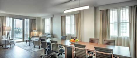 A modern conference room with a long table, several chairs, and a fruit bowl.