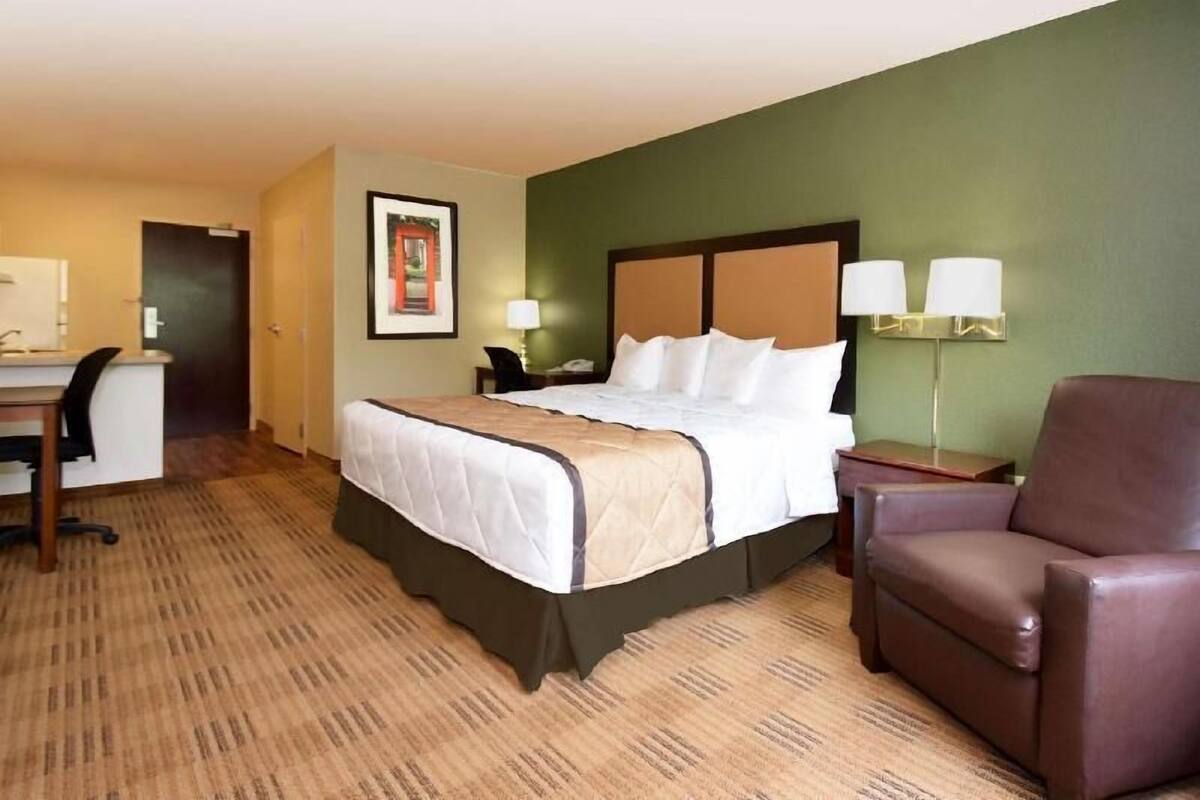 A hotel room with a bed, desk, chair, and two bedside lamps.