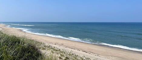 Une plage avec un ciel dégagé et des vagues calmes.