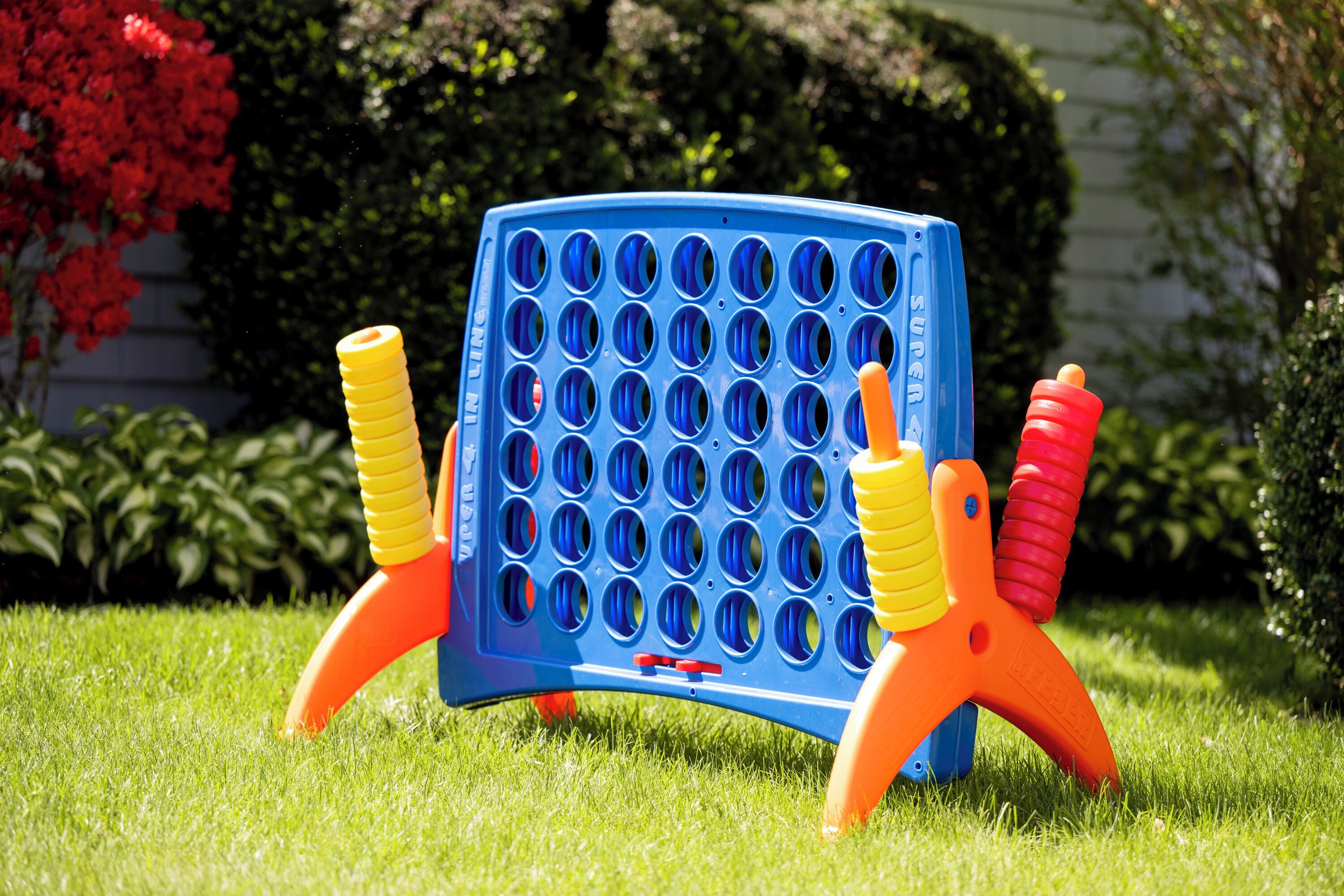 A blue and orange game board with multiple holes, set on a grassy lawn.