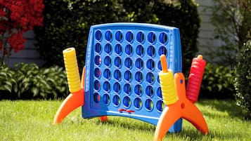 A blue and orange game board with multiple holes, set on a grassy lawn.