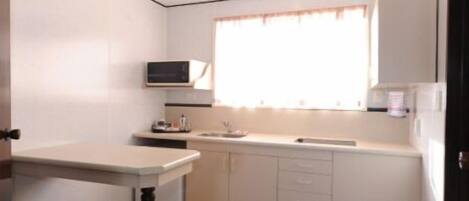 A compact kitchen with a microwave, sink, and cabinets.