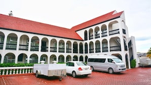 Un edificio con techo de tejas rojas y paredes blancas, con varios balcones y un corredor cubierto.