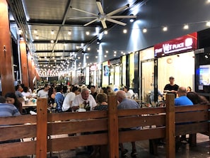 A bustling indoor dining area with wooden benches and tables, ceiling fans, and string lights. - Sunnybank Star Hotel & Apartments (Eight Mile Plains)