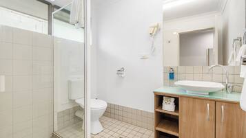 A modern bathroom with a glass shower enclosure, a toilet, a sink with a mirror, and a towel rack.