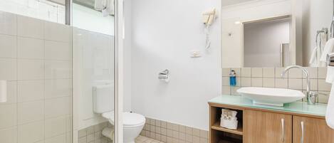 Une salle de bain moderne avec une douche à parois de verre, des toilettes, un lavabo avec un miroir et un porte-serviettes.