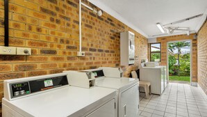 A commercial laundry area with two washing machines, a dryer, and a control panel.