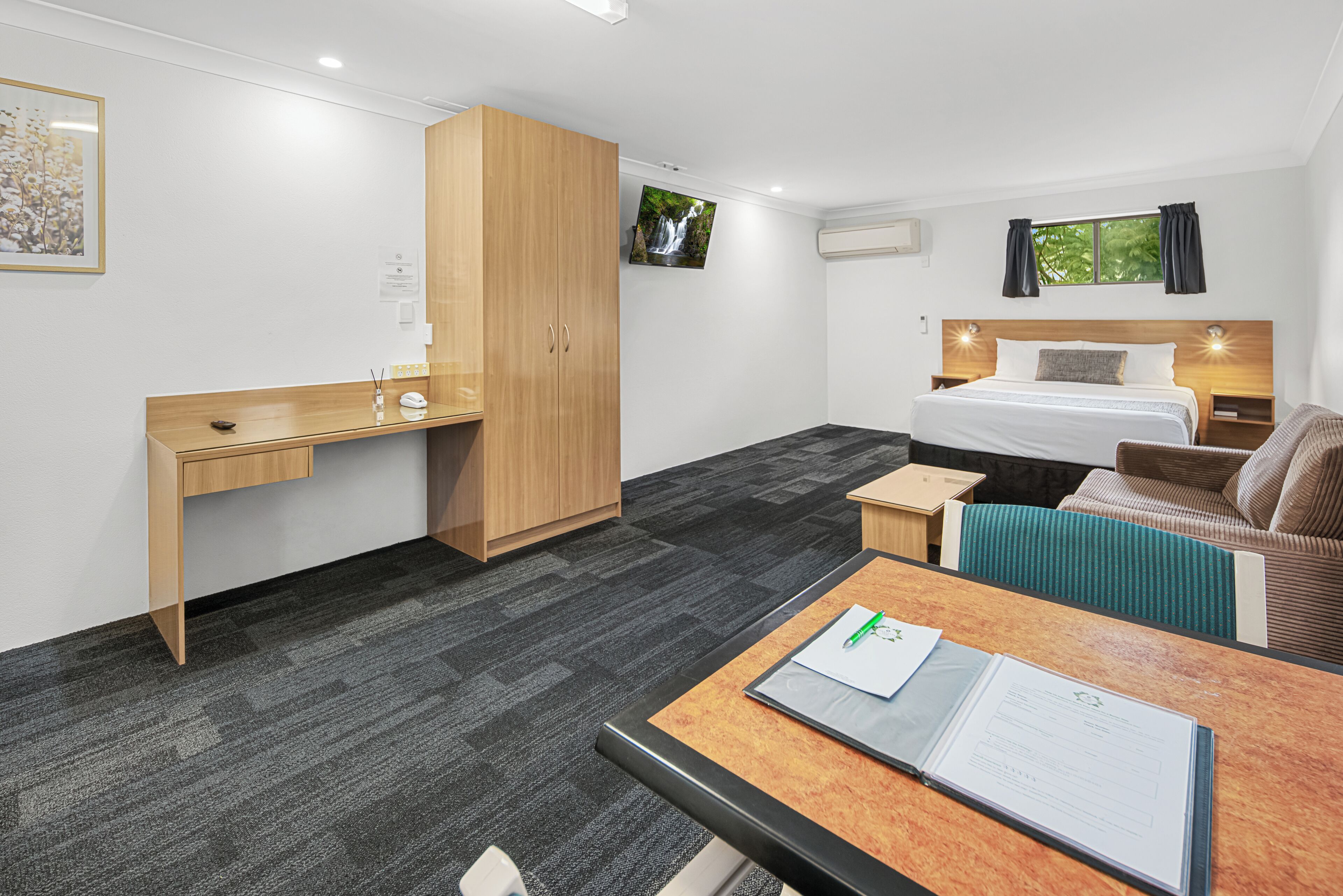 Habitación de hotel con cama, escritorio, armario, una mesita y un sofá.