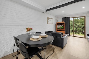A modern dining area with a round table, black chairs, and a glass vase with flowers. - Sunnybank Star Hotel & Apartments (Eight Mile Plains)