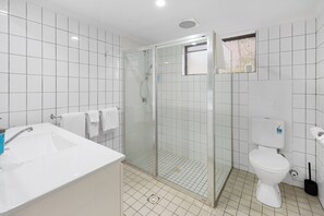 A bathroom with a glass-enclosed shower, a white sink, and a toilet. - Sunnybank Star Hotel & Apartments (Eight Mile Plains)