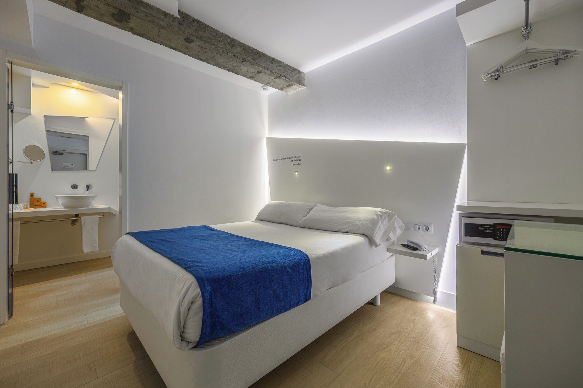 Un dormitorio moderno con cama, mesita de noche y un mini refrigerador incorporado.