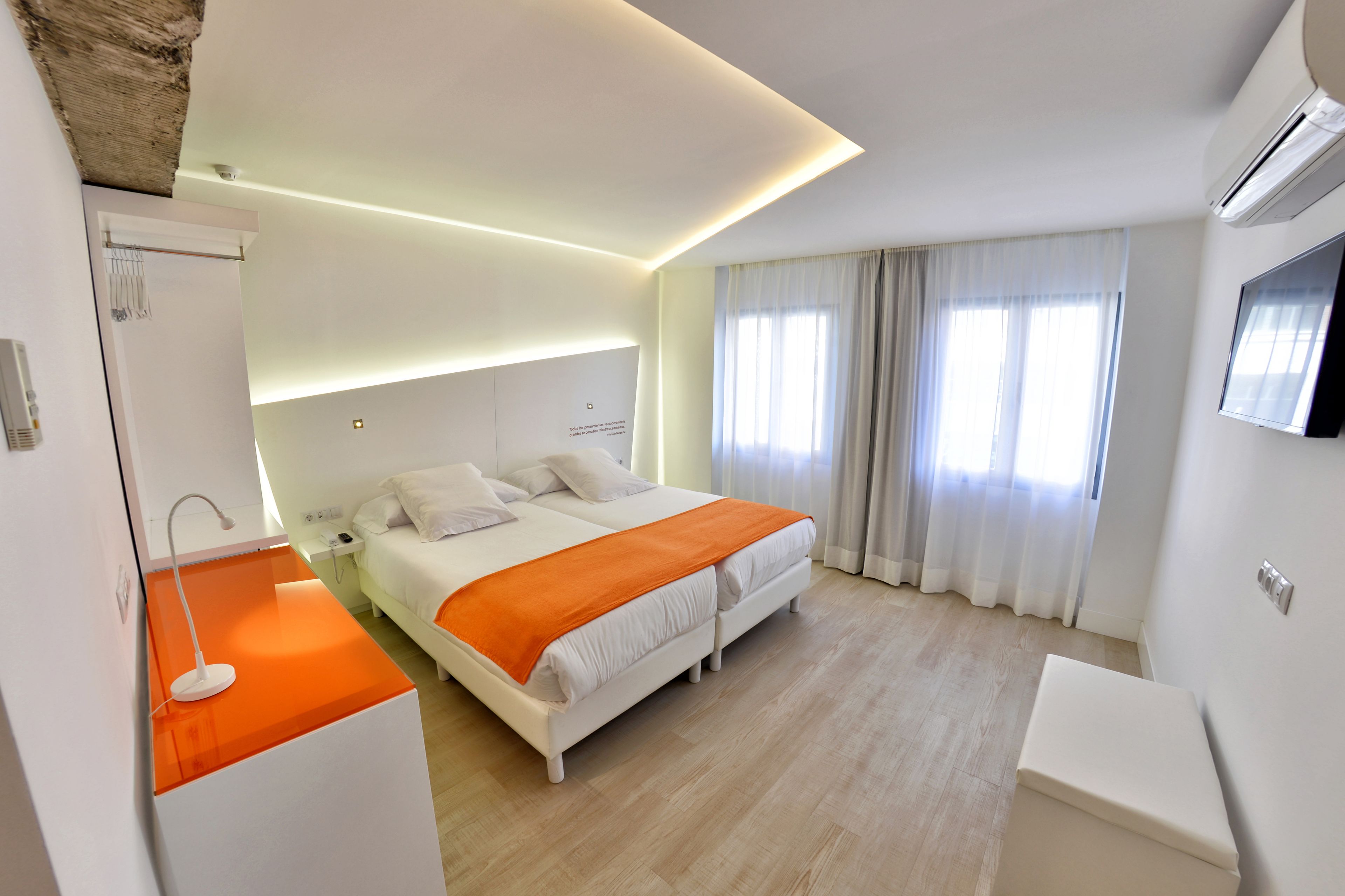 A modern hotel room with a bed, bedside table, and a TV mounted on the wall.