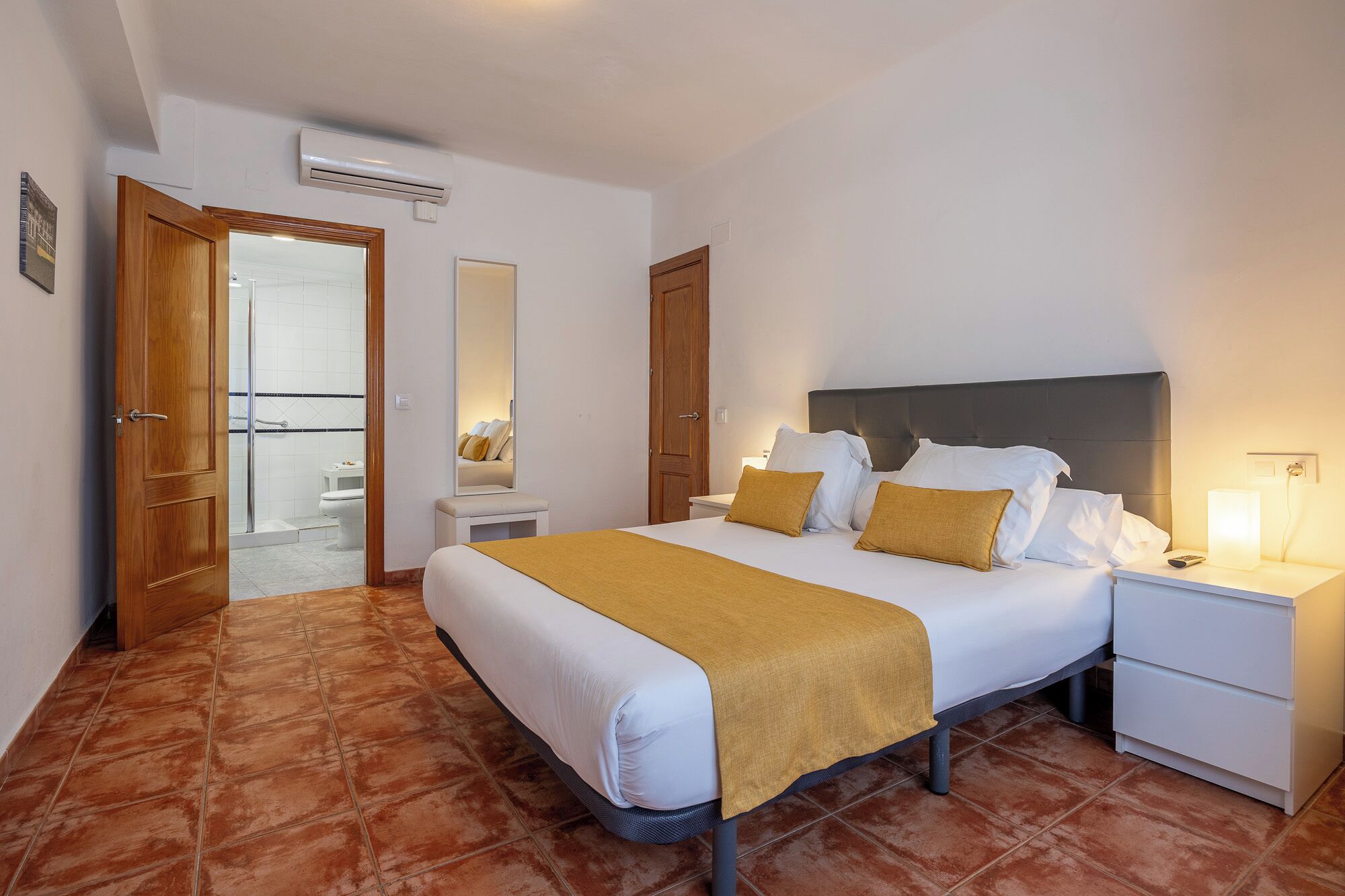 A hotel room with a bed, bedside table, and a bathroom visible through an open door.
