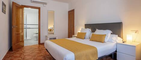 Une chambre d’hôtel avec un lit, une table de chevet et une salle de bain visible à travers une porte ouverte.