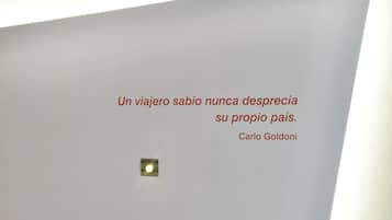 Un dormitorio moderno con una cama blanca, una mesita de noche y una lámpara de pared.