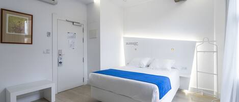 Ein modernes Hotelzimmer mit einem Bett, einer Bank, einer Klimaanlage und einem Kleiderhaken.