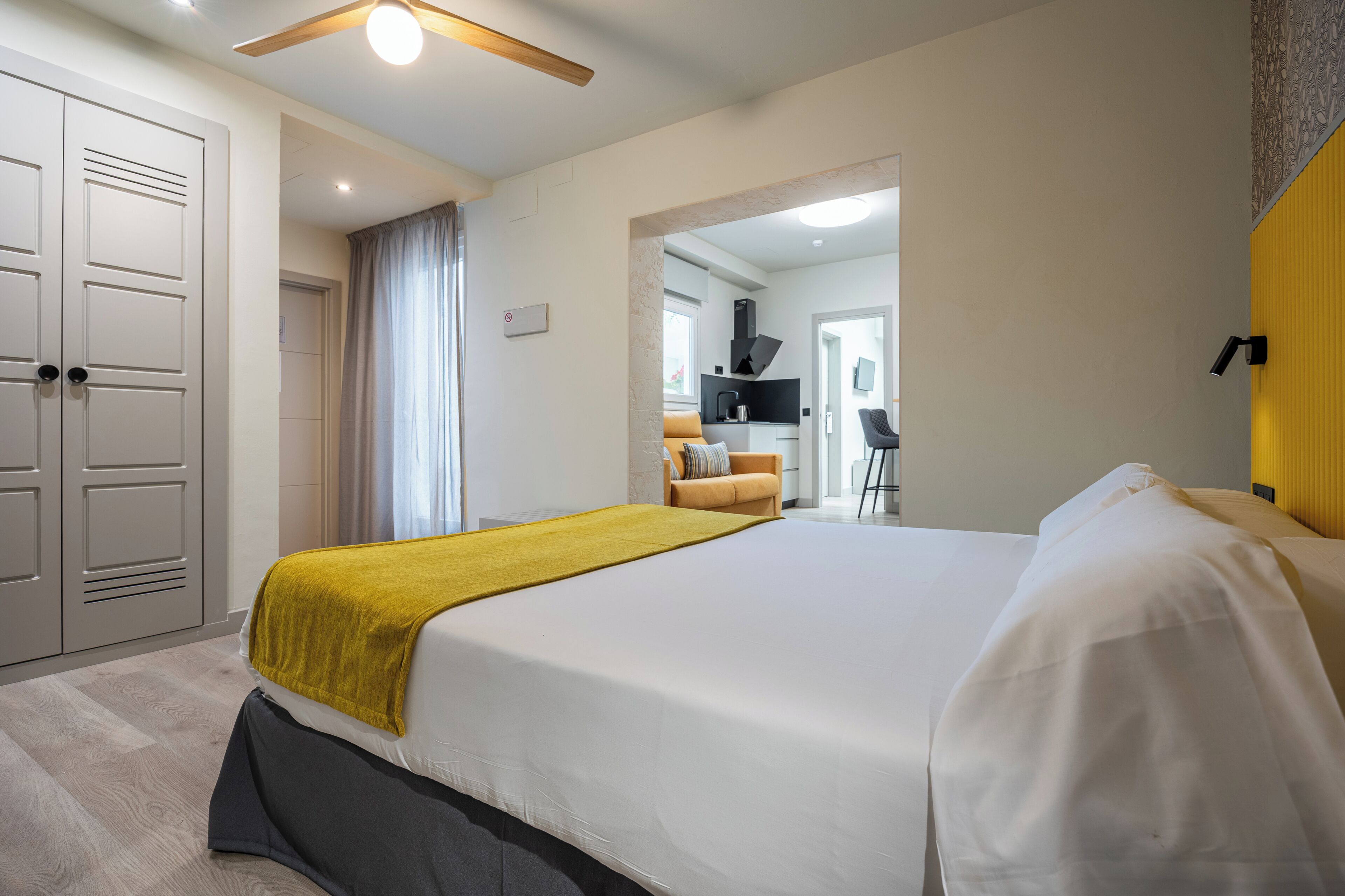Una habitación de hotel con una cama grande, un armario, un baño y una kitchenette.