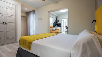 Una habitación de hotel con una cama grande, un armario, un baño y una kitchenette.