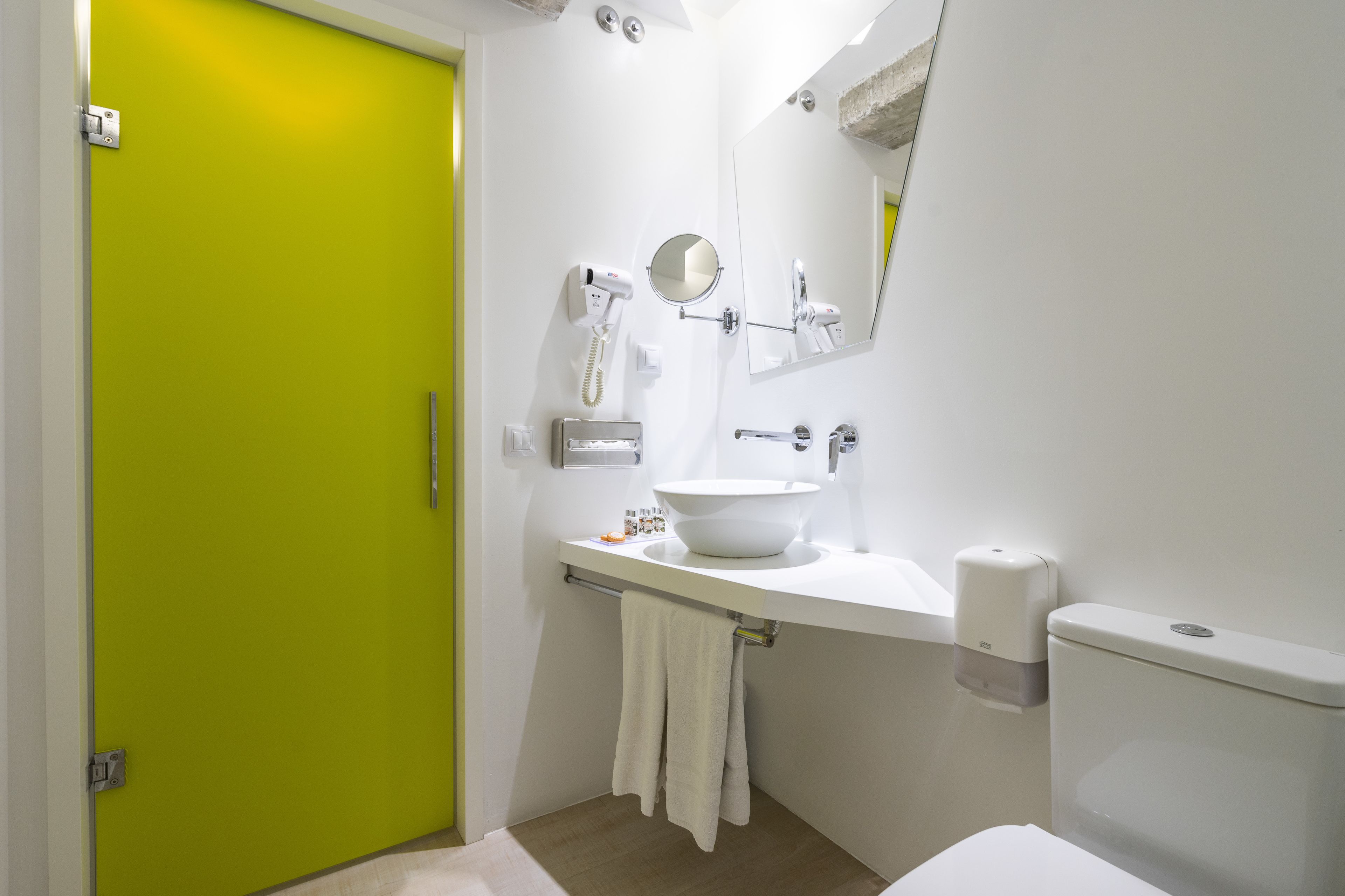Een badkamer met een wit wastafel, een spiegel, een handdoek en een toilet.