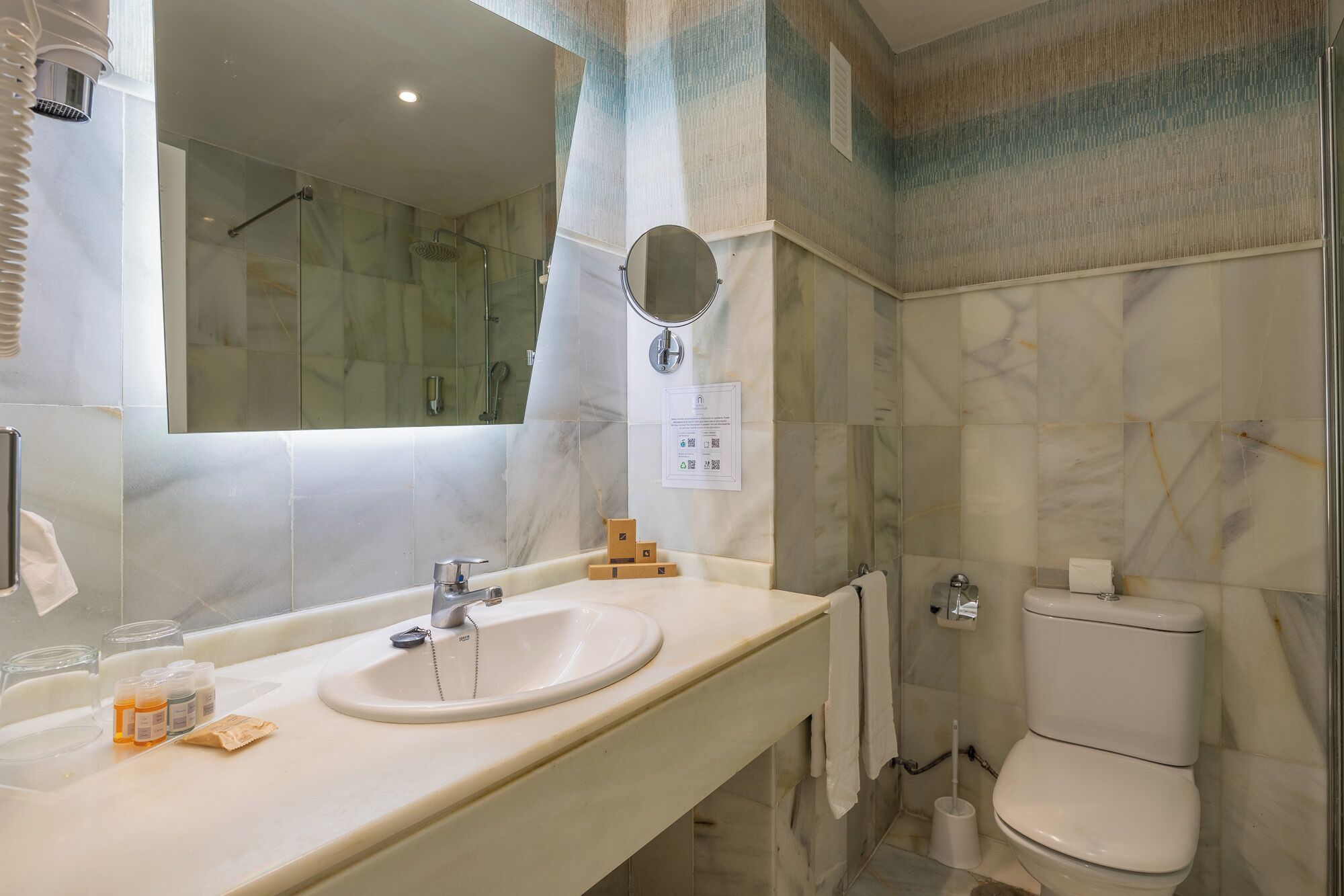 A bathroom with a sink, mirror, toilet, and shower.