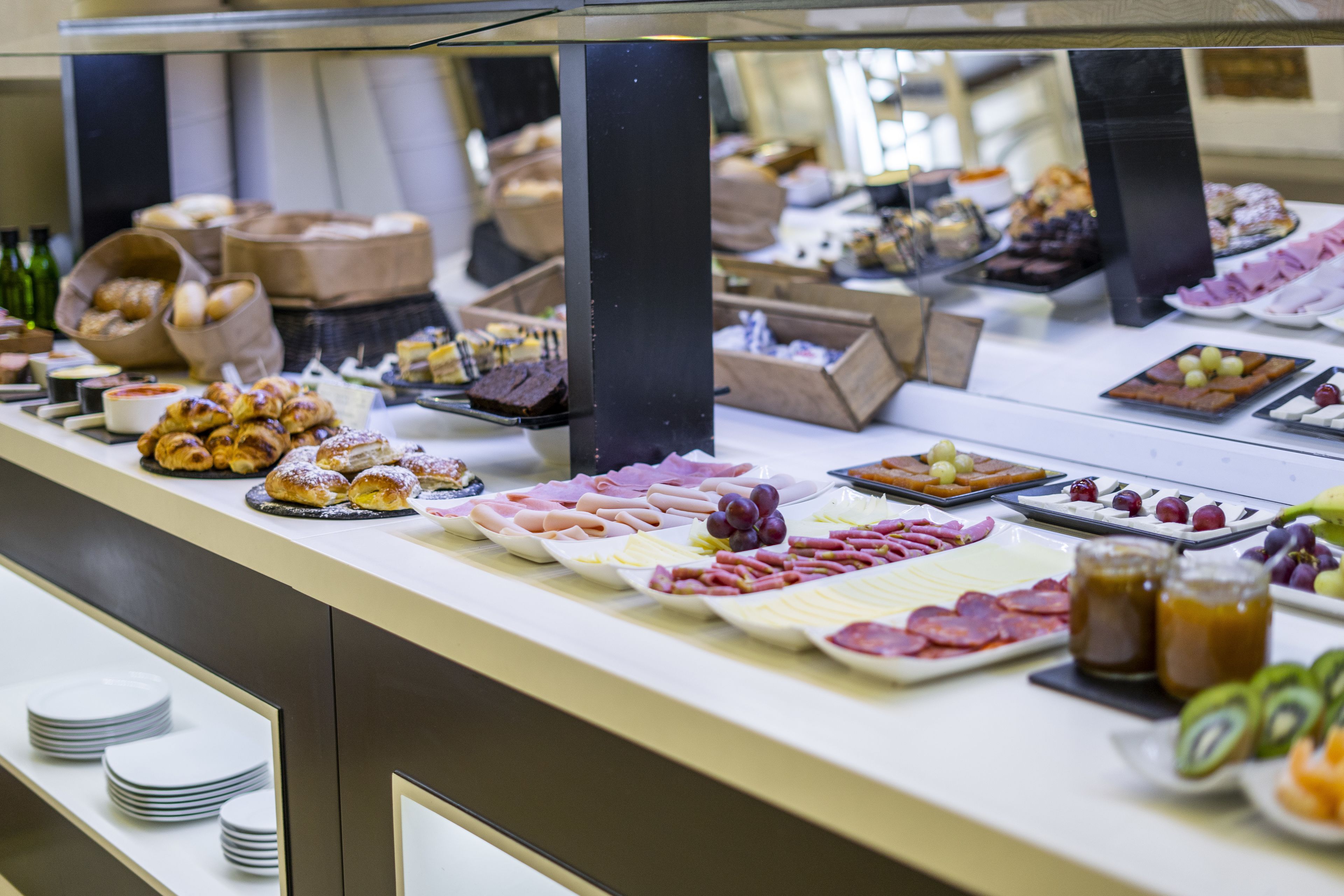 A buffet with various food items including pastries, meats, and cheeses.