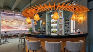 A bar area with a curved counter, three bar stools, and hanging pendant lights.