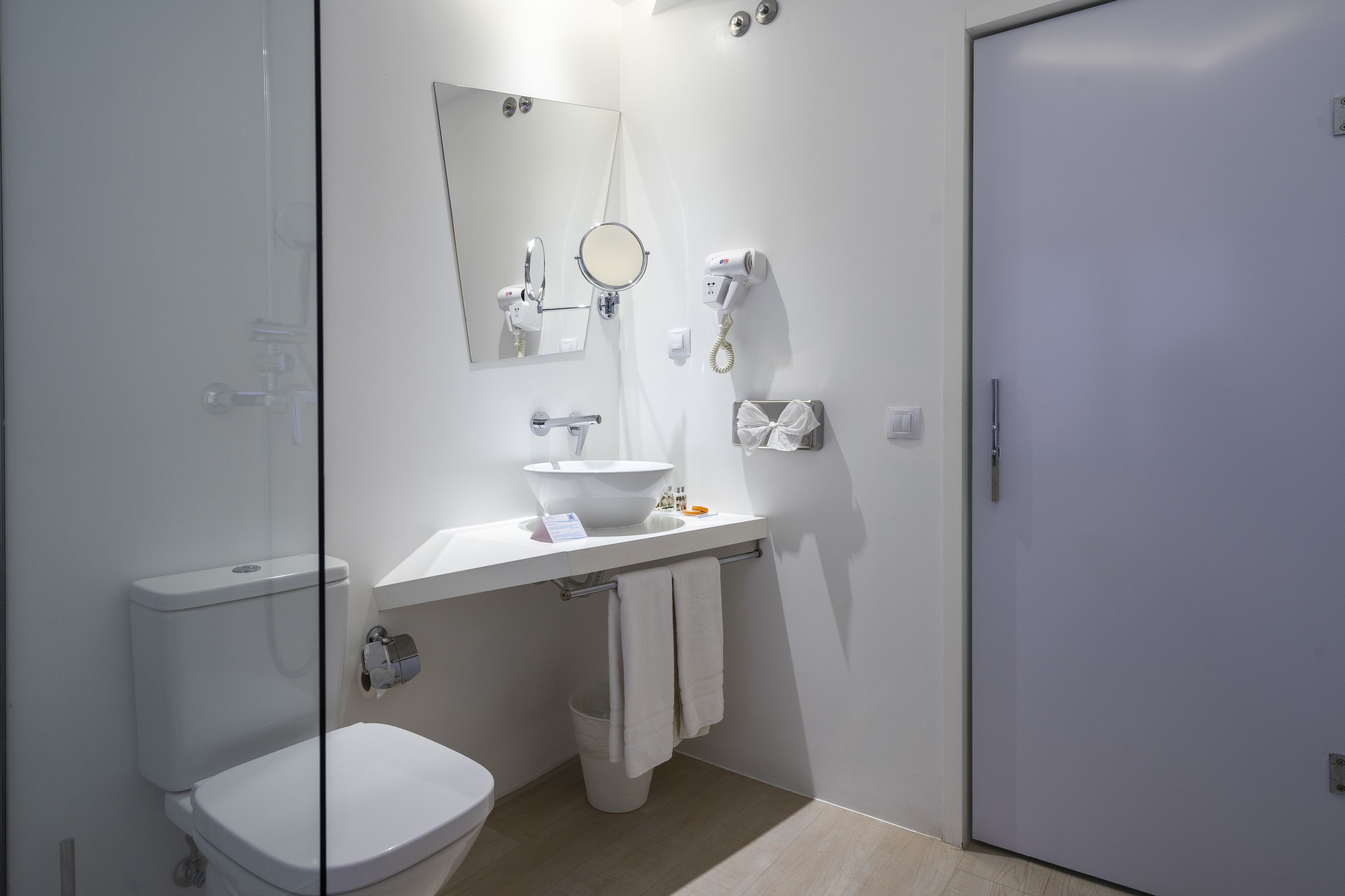 A modern bathroom with a toilet, sink, mirror, and towel rack.