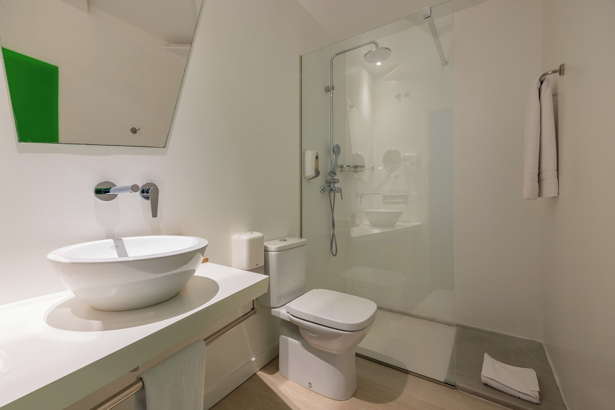 Une salle de bain moderne avec un lavabo blanc, des toilettes et une douche à parois de verre.