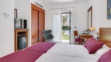 Habitació d'hotel amb un llit, una taula, una cadira, un televisor i vistes a l'exterior.