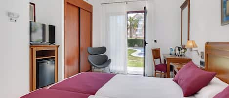 A hotel room with a bed, a desk, a chair, a television, and a view of the outdoors.