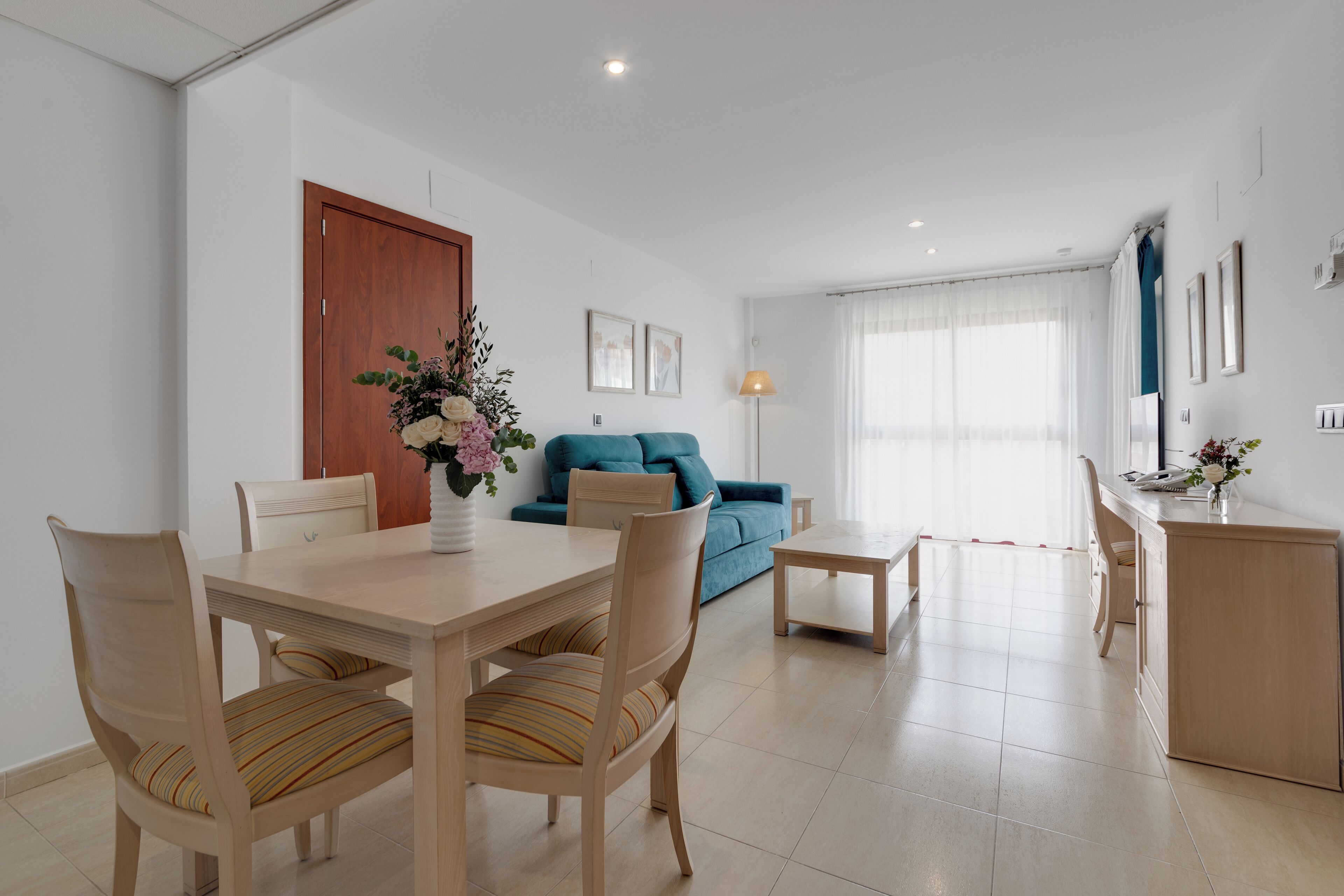 A modern living room with a dining table, chairs, a sofa, and a small coffee table.