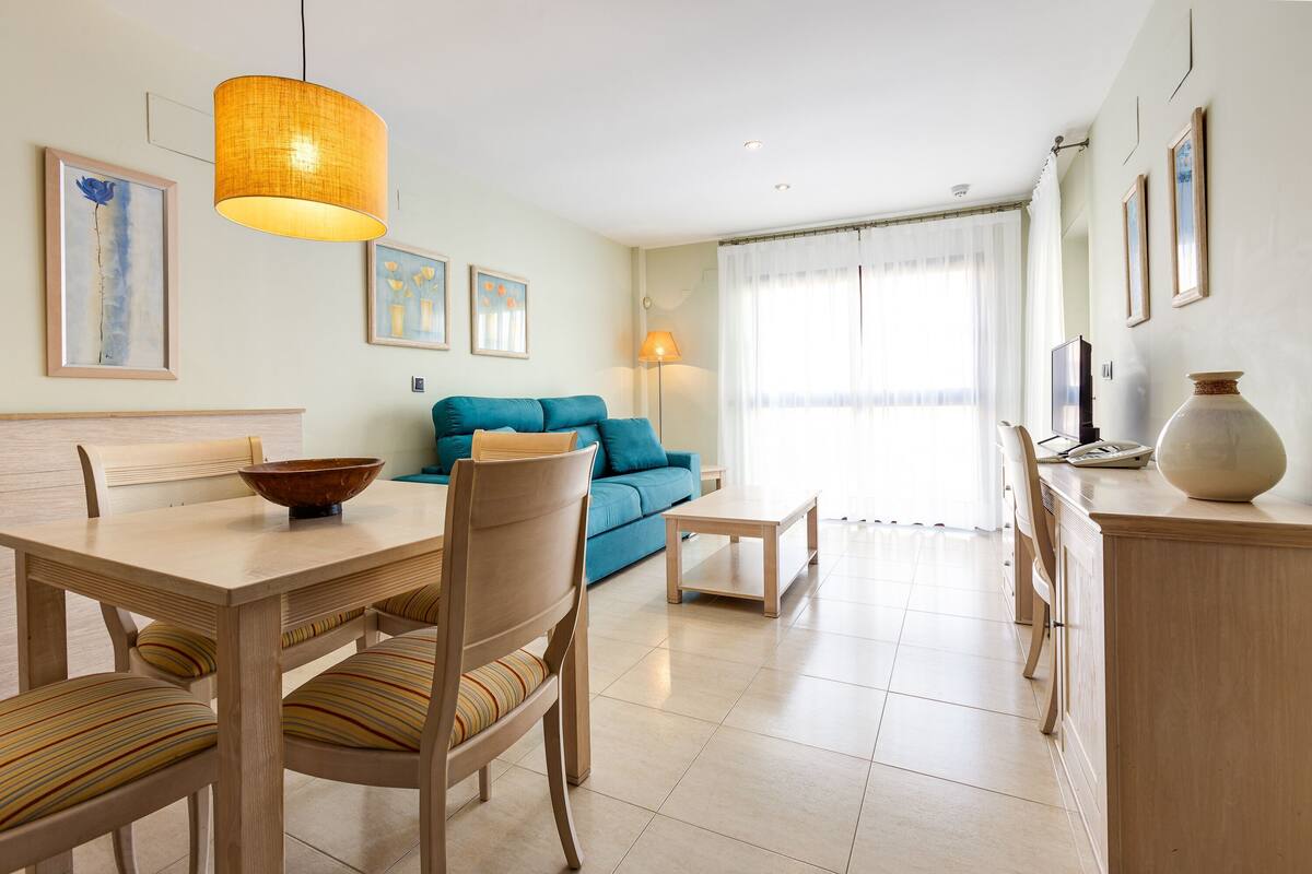 A modern living room with a dining table, chairs, a sofa, and a coffee table.