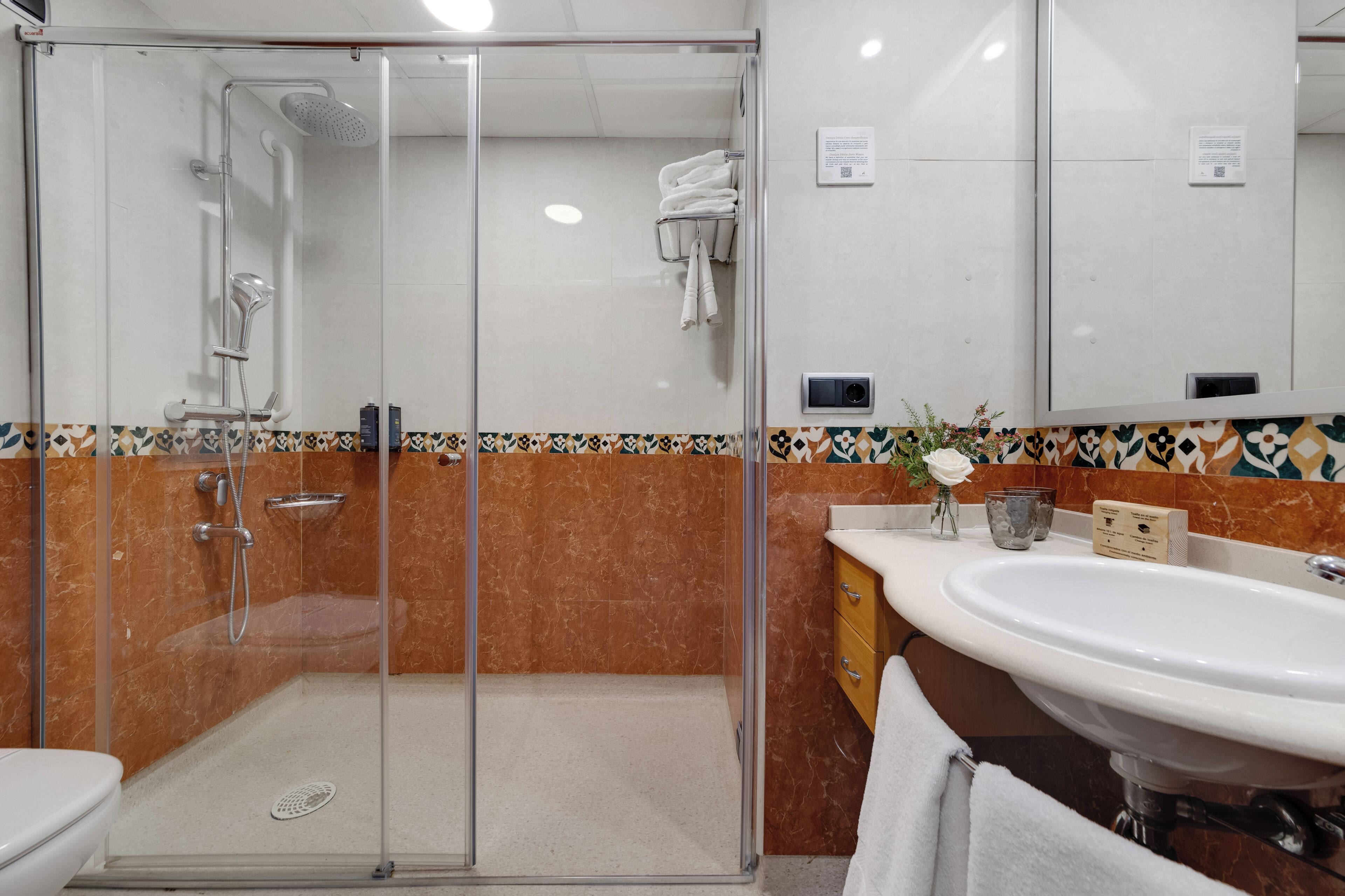 Un baño moderno con ducha de vidrio, un lavabo blanco y salpicadero de azulejos.