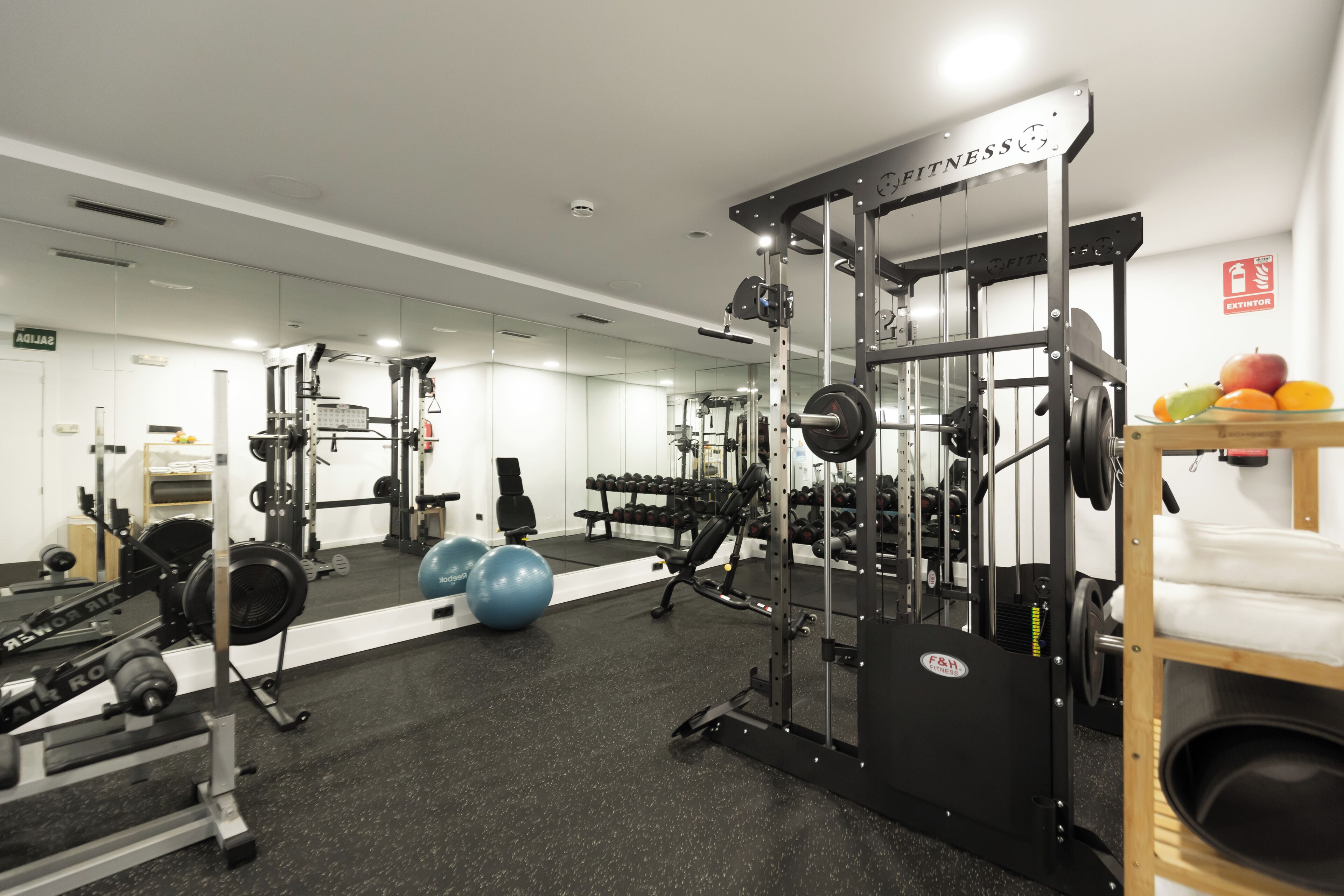 A gym with weightlifting equipment, exercise balls, and dumbbells.
