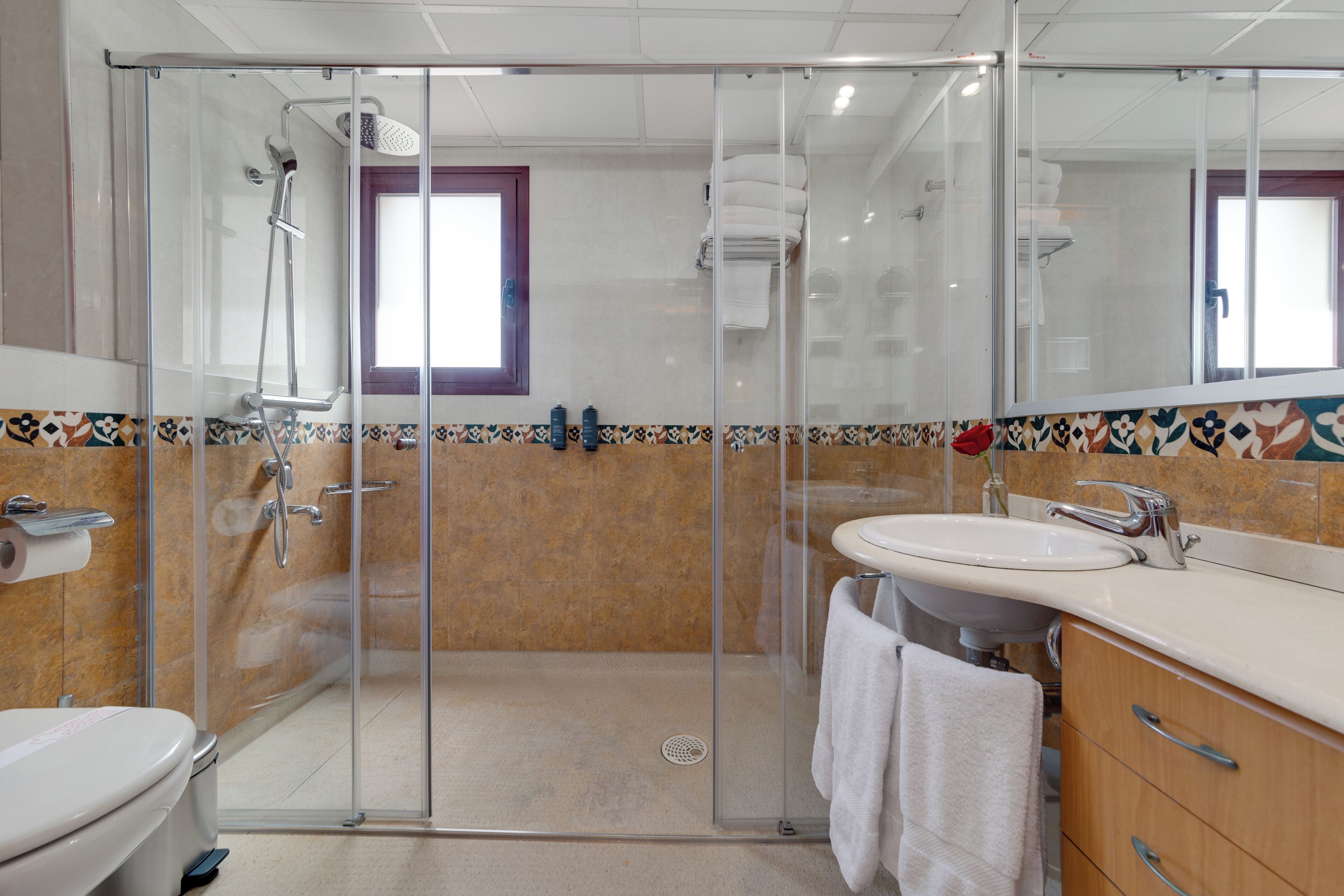 A modern bathroom with a glass-enclosed shower, a white sink, and a toilet.