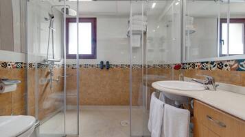 A modern bathroom with a glass-enclosed shower, a white sink, and a toilet.