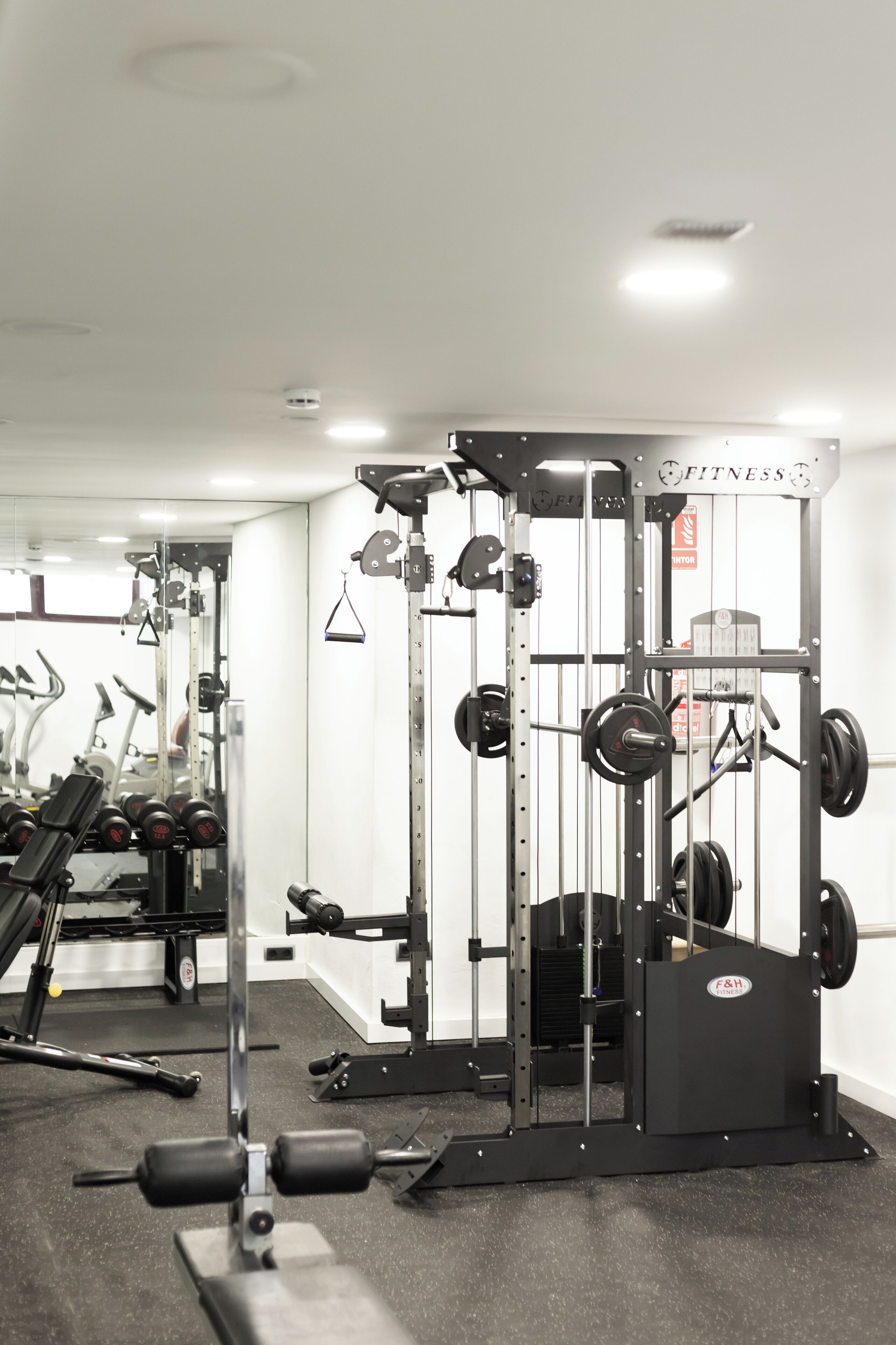 Un gimnasio con equipo de levantamiento de pesas, espejos y un diseño moderno y limpio.