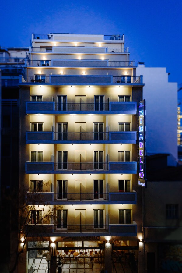 A multi-story hotel with balconies and a neon sign. - The Athens Mirabello (Athens)