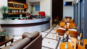 A modern lobby with a bar area, leather seating, and a tiled floor. - The Athens Mirabello (Athens)
