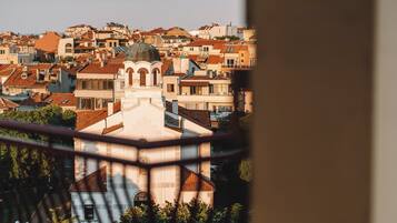 A view of a densely packed urban area with historic buildings, including a prominent church with a dome, through a window with a metal railing.