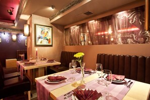 A restaurant interior with tables set for dining, a vase with flowers, and a painting on the wall. - Saint George Hotel & Spa (Pomorie)