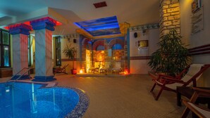 A swimming pool with a glass enclosure, a seating area with chairs, and a stone wall with arches. - Saint George Hotel & Spa (Pomorie)
