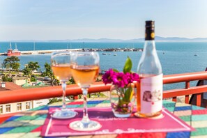 A table with a bottle and two glasses, overlooking a harbor with boats and a distant coastline. - Saint George Hotel & Spa (Pomorie)