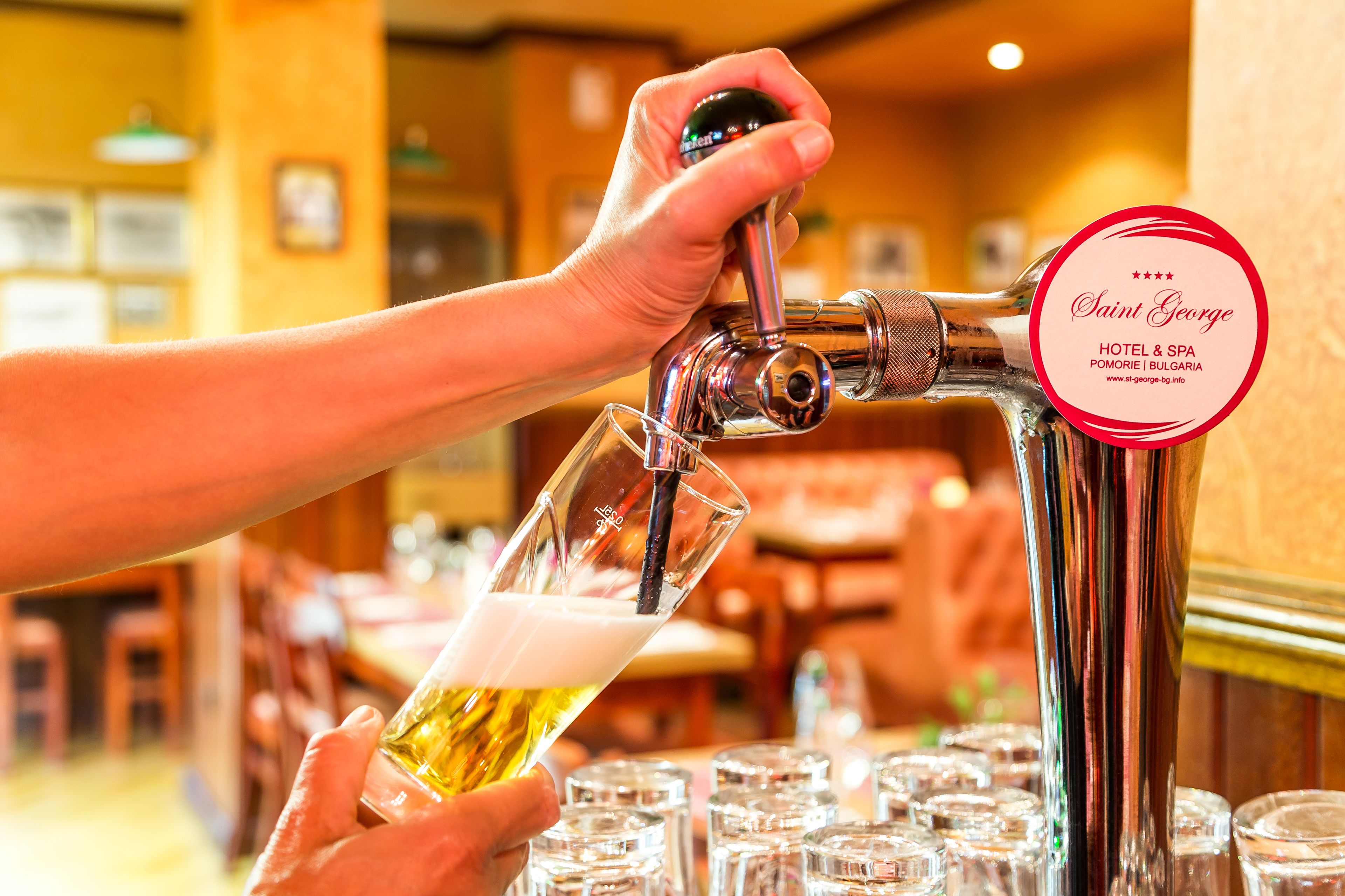 A hand pouring beer from a tap into a glass.