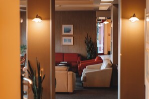 Eine Hotellobby mit einem roten Sofa, beigen Sesseln und zwei gerahmten Bildern an der Wand.