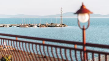 A pier with boats and a tall structure, viewed from a distance with a railing in the foreground.