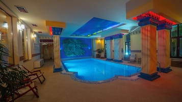Zwembad met een blauwe mozaïekrand, omringd door kolommen met rode verlichting, en een groot muurdecor.