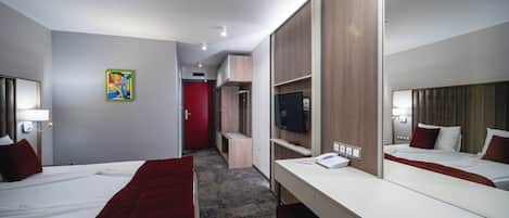 A hotel room with two beds, a TV, a desk, and a mirror.