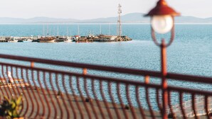Un muelle con barcos y una estructura alta, visto desde lejos con una barandilla al frente.
